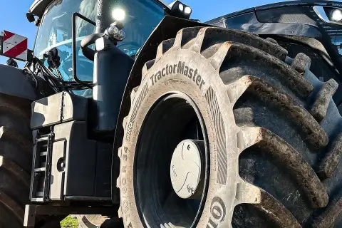 Ciągnik z masywnymi oponami, w tym jedna z napisem "TractorMaster", idealny zamiennik opon rolniczych.