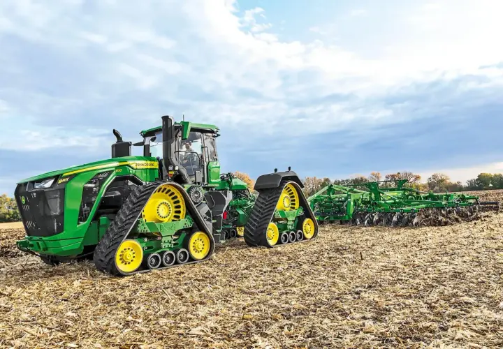 Potężny John Deere 9RX 830 z gąsienicami i pługiem na jesiennym polu.