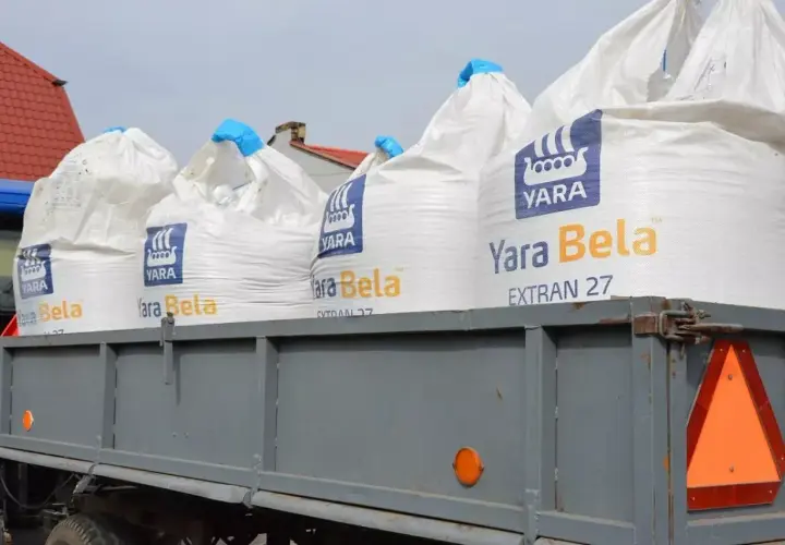 Na przyczepie stoją worki nawozu Yara Bela EXTRAN 27. Właściwe saletrzak dawkowanie zapewni plonom optymalny wzrost.