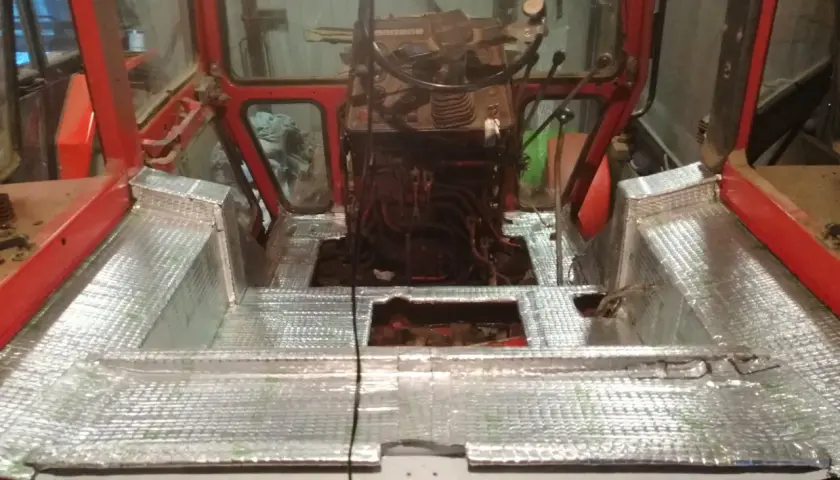 Wnętrze kabiny ciągnika z nałożonym materiałem wygłuszającym. Prace nad wygłuszeniem kabiny ciągnika w toku.