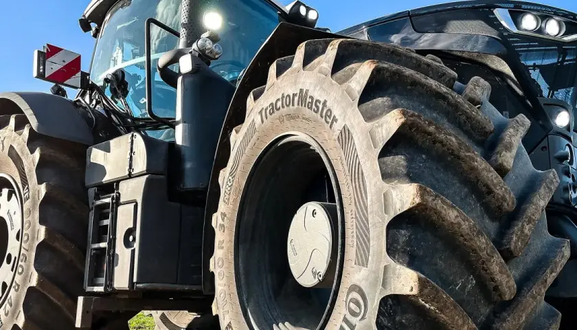 Ciągnik z masywnymi oponami, w tym jedna z napisem "TractorMaster", idealny zamiennik opon rolniczych.