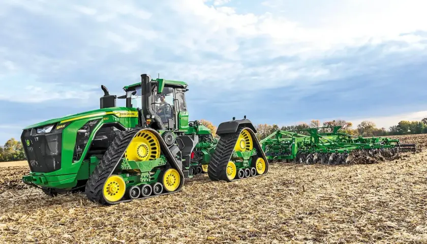 Potężny John Deere 9RX 830 z gąsienicami i pługiem na jesiennym polu.