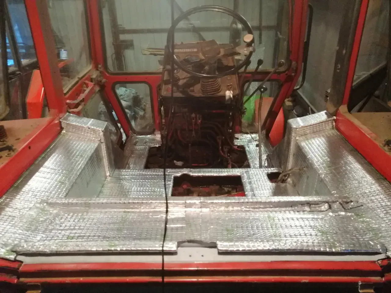 Wnętrze kabiny ciągnika z nałożonym materiałem wygłuszającym. Prace nad wygłuszeniem kabiny ciągnika w toku.