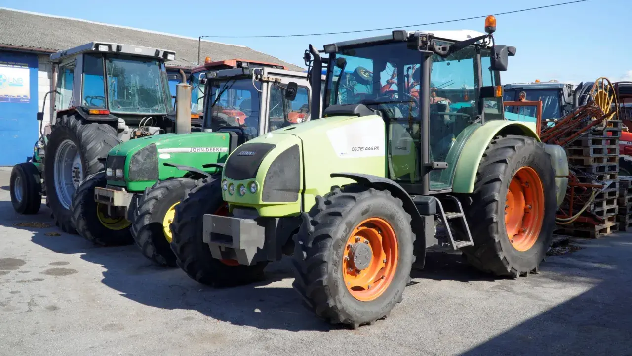 Kilka ciągników rolniczych, w tym zielony John Deere i jasnoszary Claas. Zastanawiasz się, ile motogodzin to dużo dla takiego sprzętu?