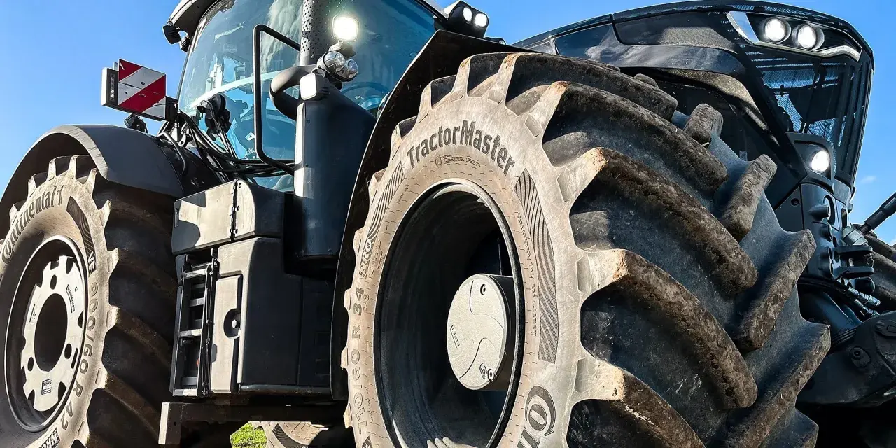 Ciągnik z masywnymi oponami, w tym jedna z napisem "TractorMaster", idealny zamiennik opon rolniczych.