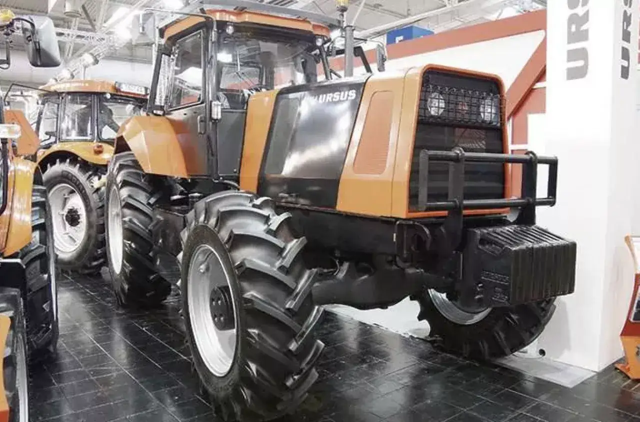 Pomarańczowy, potężny traktor Ursus, największy z tej serii, prezentuje swoje masywne opony i kabinę.