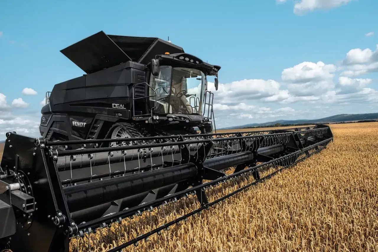 Czarny kombajn Fendt Ideal 10T w akcji, pokazujący jego imponującą wydajność podczas żniw na złotym polu pszenicy.